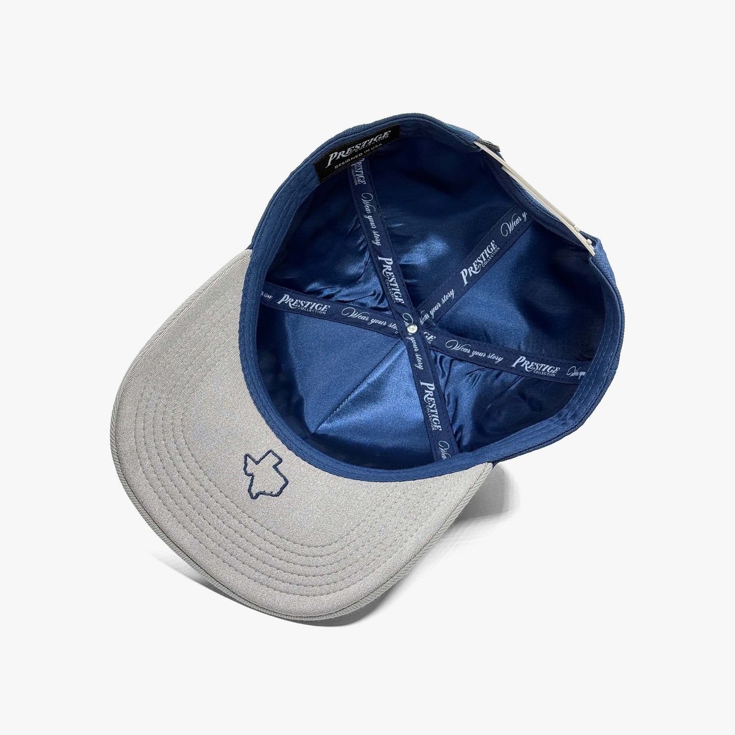 Underside of Dallas snapback hat showing navy satin lining and Prestige Collection "Wear your story" tape