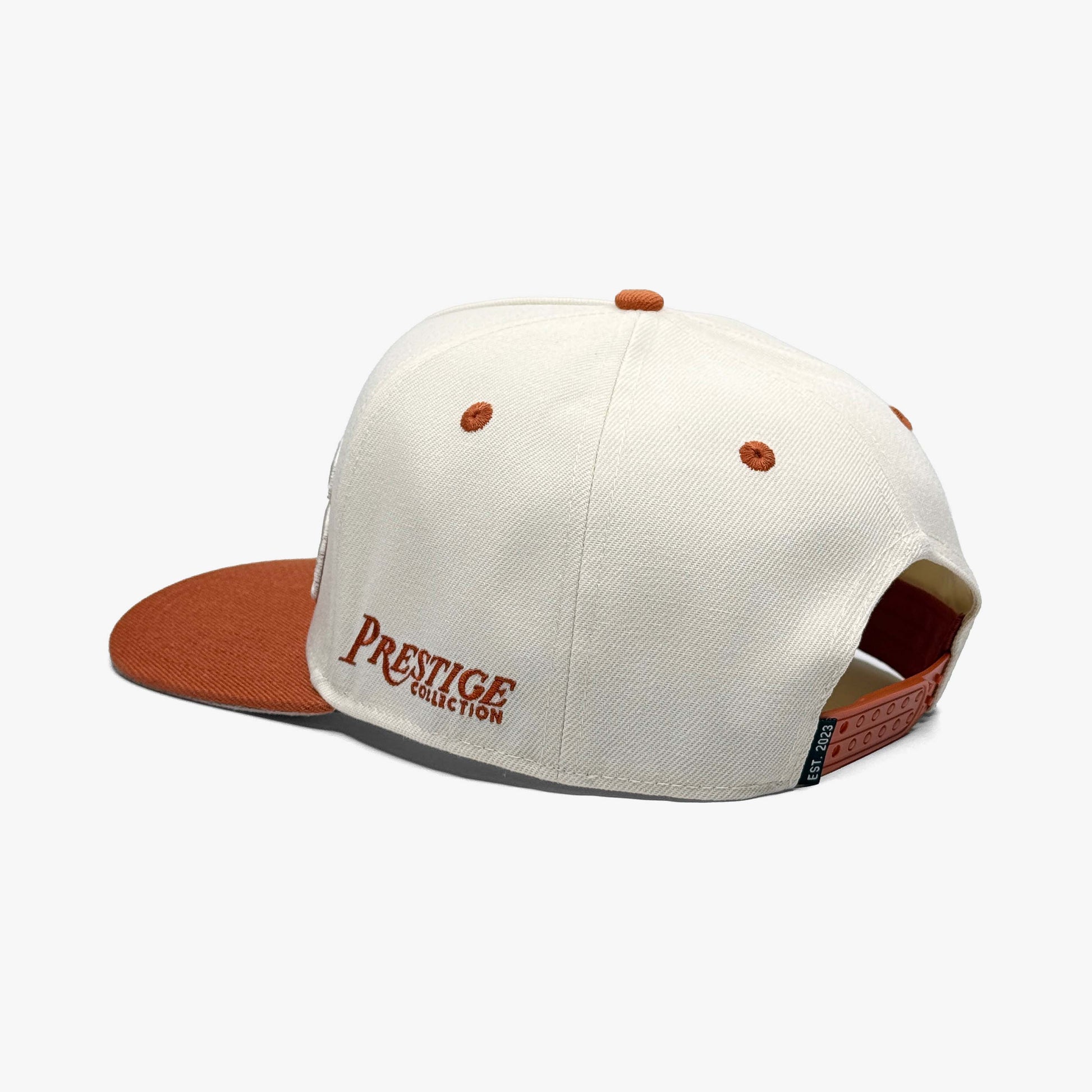 Back view of cream Texas snapback hat with burnt orange adjustable strap, Est. 2023 tag