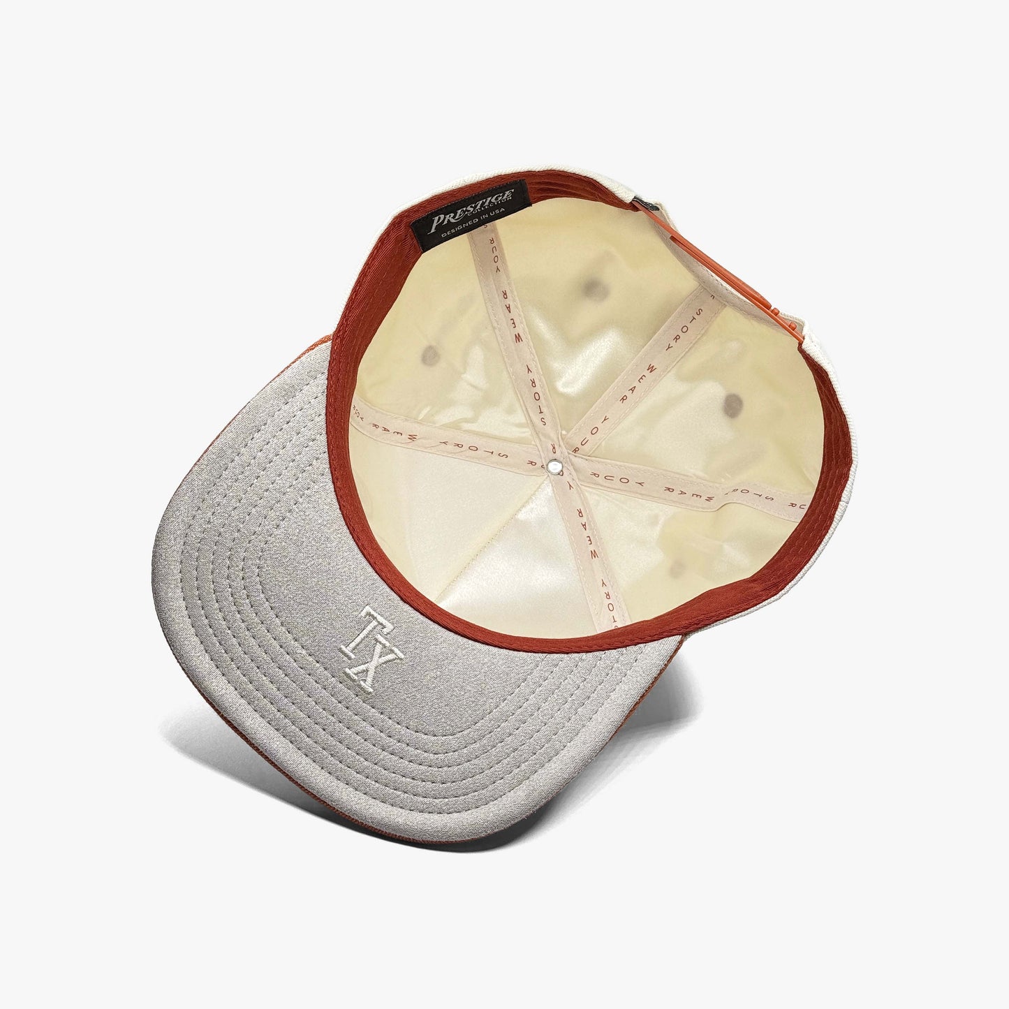 Underside of Texas snapback hat showing cream satin lining and "TX" embroidery on the brim