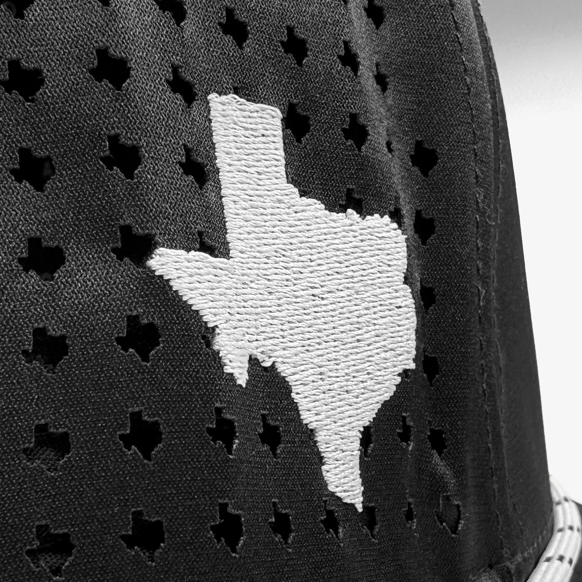 Black cap with white embroidered Texas shape on a textured background